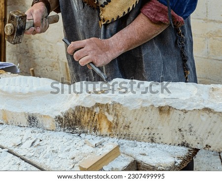 Medieval re-enactment of a stonemason shaping the stone with a hammer and chisel