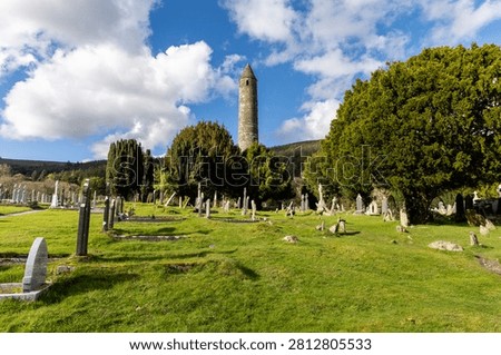 Medieval Round Tower surrounded by Celtic crosses at Glendalough, County Wicklow, Ireland