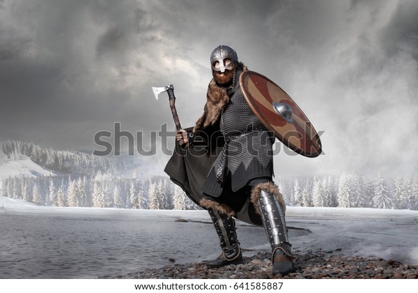 Medieval Scandinavian warrior Viking in full outfit\
on shore of winter sea
