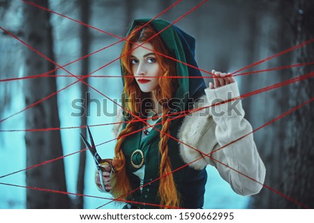 The medieval sorceress cuts the threads of fate in the thicket of the winter forest. Historical reconstruction of the Middle Ages. Fairy tales.