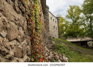 Medieval Stone Castle Wall with Autumn Ivy and Tower in Scenic Green Landscape, In background, castle with tower and dome, surrounded by trees, Historic European Architecture Surrounded by Nature - Powered by Shutterstock