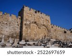 The medieval stone walls and ramparts of the Old City of Jerusalem and the cemetery and sealed twin arches of the Mercy Gate or Golden Gate with twin arches. 