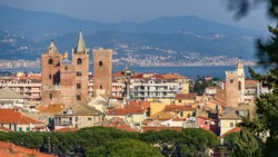 The Medieval Towers In The Cityscape Of The Ligurian Village Of Albenga, Situated On The Italian Riviera