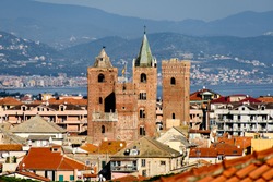 The Medieval Towers In The Cityscape Of The Ligurian Village Of Albenga, Situated On The Italian Riviera