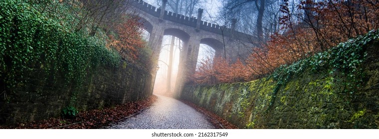 Medieval Viaduct In The Night Autumn Forest In Fog And A Road With Paving Stones