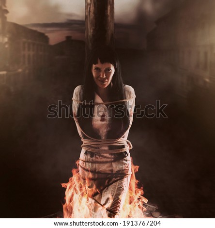 Medieval witch is tied to a wooden post and burns at the stake and smile