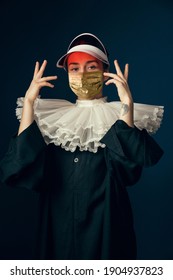 Medieval Young Woman As A Nun In Vintage Clothing And Golden Face Mask With Red Beach Cap On Blue Background. Concept Of Comparison Of Eras, Fashion, Ad, Healthcare. Royal Person Protected From Covid.