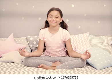 Meditate Before Go To Bed. Girl Child Sit On Bed In Her Bedroom. Kid Prepare To Go To Bed. Pleasant Time For Evening Meditation. Girl Kid Long Hair Cute Pajamas Relaxing And Meditating In Bedroom.