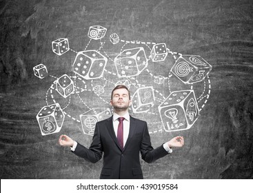 Meditating Businessman Standing Against Chalkboard With Connected Dice Sketch. Game And Probability Theory