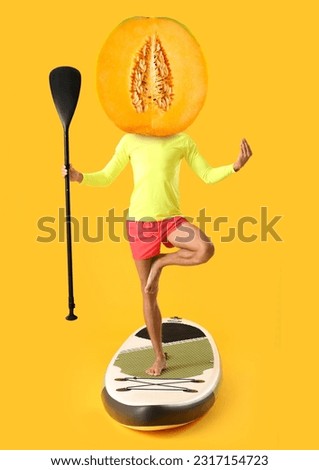 Meditating man with sup board and juicy melon instead of his head on orange background