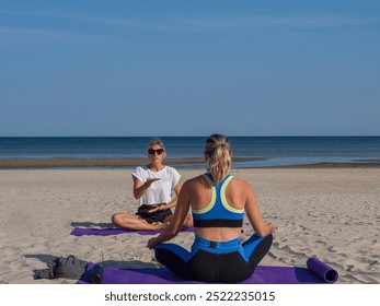 Meditating on the sandy beach follows yoga poses shown by a skilled teacher. Yoga stretches align with the waves rhythm, merging yoga practice with the oceans tranquil ambiance. - Powered by Shutterstock