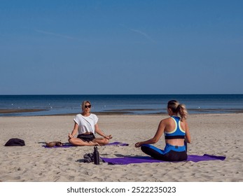 Meditating on the sandy beach follows yoga poses shown by a skilled teacher. Yoga stretches align with the waves rhythm, merging yoga practice with the oceans tranquil ambiance. - Powered by Shutterstock