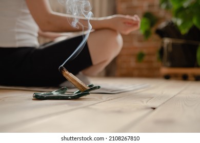 meditating with palo santo aroma stick, mental health - Shutterstock ID 2108267810