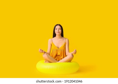 Meditating Young Woman With Inflatable Ring On Color Background