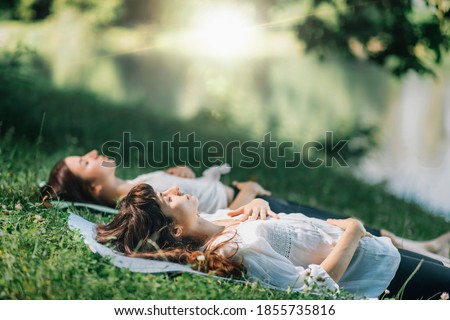 Meditation by the water. Two young women lying by the water and meditating