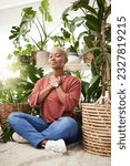 Meditation, plant and black woman relax in home for wellness, zen mindset and calm energy. Nature, happy and face of female person meditate on floor with eco friendly ferns, leaves and house plants