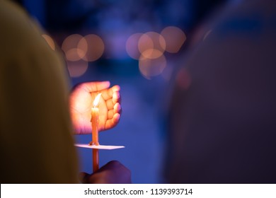 Meditation Spirit Concept, Candle On Hand Holding. Candle Burning On Bokeh Light And Blurred Black Background. Right Hand Holding It And Left Hand Protect Wind Blowing It For Burn Growing  On Night