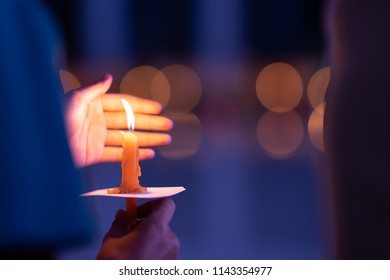 Meditation Spirit Concept, Candle On Hand Holding. Candle Burning On Bokeh Light And Blurred Black Background. Right Hand Holding It And Left Hand Protect Wind Blowing It For Burn Growing  On Night