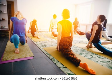 Meditation Teacher Shows Exercises From Yoga And Stretching For A Group Of Girls And Guys. Concept Of Team Health And Coaching Of The Splash.