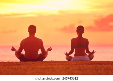 Meditation Yoga Couple Meditating At Serene Beach Sunset. Girl And Man Relaxing In Lotus Pose In Calm Zen Moment In The Ocean During Yoga Holiday Class At Resort Retreat.