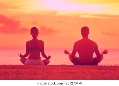 Meditation Yoga Couple Meditating At Serene Beach Sunset. Girl And Man Relaxing In Lotus Pose In Calm Zen Moment In The Ocean During Yoga Holiday Class At Resort Retreat.