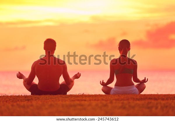 Meditation yoga couple\
meditating at serene beach sunset. Girl and man relaxing in lotus\
pose in calm zen moment in the ocean during yoga holiday class at\
resort retreat.