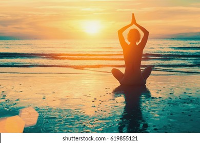 Meditation Yoga Silhouette Of Woman On The Sea Beach At Sunset.