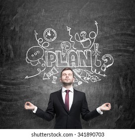 Meditative Businessman Is Dreaming About Building Of A Business Plan For Business Development. Business Plan Sketch Is Drawn On The Black Chalkboard.