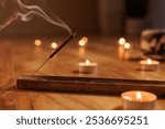 Meditative moment with incense and candles, smoking aromatic incense stick close up. aromatherapy