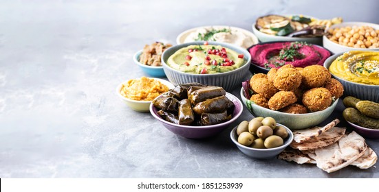 Mediterranean appetizer concept. Arabic traditional cuisine. Middle Eastern meze with pita, olives, hummus, stuffed dolma, falafel balls, pickles, babaganush, vegetables, pomegranate, eggplants. - Shutterstock ID 1851253939