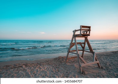 Mediterranean beach with wooden lifeguard chair in sunset time, Oliva Beach in Valencia province, Spain. Teal and orange style.