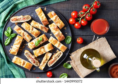 Mediterranean Borek Of Filo Dough With Minced Meat And Tomatoes, Onion, Sumac Spice, Served On A Black Tray With Basil On Top, Fresh Tomato Juice On A Wooden Table, Overhead