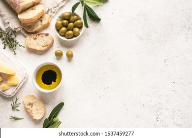 Mediterranean food background. Fresh italian ciabatta bread with herbs, olive oil, balsamic vinegar, parmesan and olives on white background, top view, copy space.