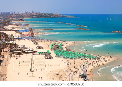 Mediterranean seaside of Tel Aviv. Beaches and old embankment (before restoration) view. Ancient Arab city of Jaffa or Yafo - the oldest part of Tel Aviv - Yafo on the horizon. Israel.