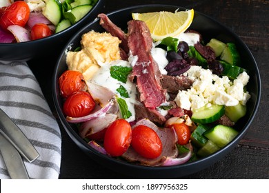 Mediterranean Steak Bowls: A Meal Of Flank Steak, Grape Tomatoes, Hummus, And Other Vegetables With Herbed Yogurt Dressing Served Over Romaine Lettuce