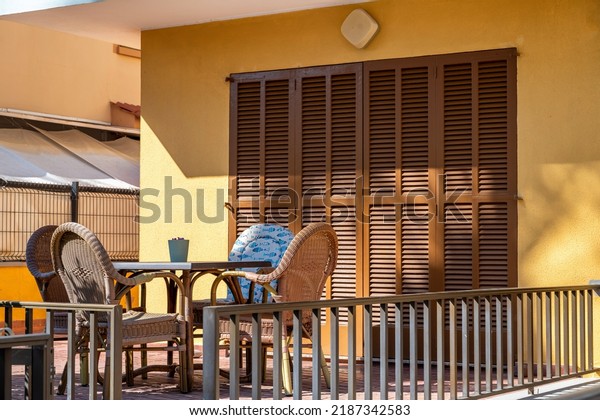 Mediterranean style terrace with garden furniture\
and wood colored louvered\
doors