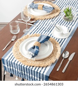 Mediterranean-Inspired Summer Table Setting Featuring Crisp White Porcelain on Natural Woven Raffia Placemats, with Bold Blue Striped Linen Table Runner and Matching Napkins,Clear Glass Stemware.