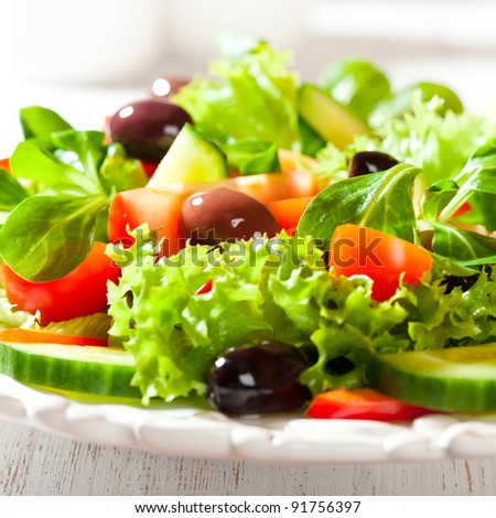 Mediterranean-style salad with kalamata olives, different tomatoes, lambs lettuce, cucumber and lettuce.  Healthy snack. Concept for a tasty and healthy meal. Close up.