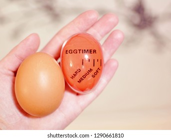 Medium Boiled Egg With An Red Egg Timer Held In Woman White Hand