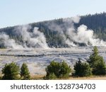Medium close up of steam rising from multiple geysers and hot springs at the Yellowstone National Park in Wyoming.