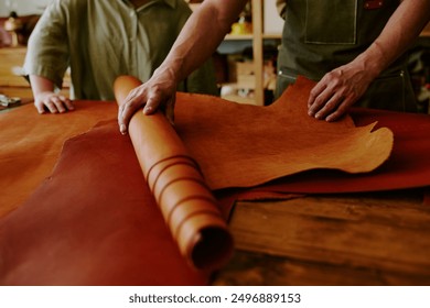 Medium close up of unrecognizable male hands rolling out chocolate leather roll while his clients hand touching material - Powered by Shutterstock