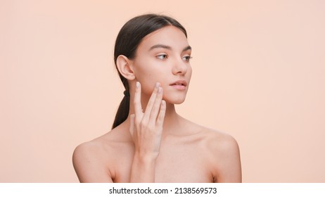 Medium close-up beauty portrait of Young slim woman who gently touches and strokes her jawline and look at the camera. Beauty and skin care concept - Shutterstock ID 2138569573