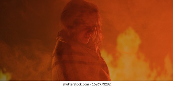 Medium close-up of a girl crying while being surrounded by flames
