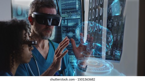 Medium close-up of a male and a female doctor examining 3D brain hologram while wearing VR headsets - Powered by Shutterstock