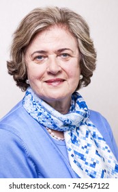 Medium Close-up Portrait Of An Elegant Amd Well Maintained Senior Woman (in Her Late 60's) Smiling A Toothy Smile To The Camera.