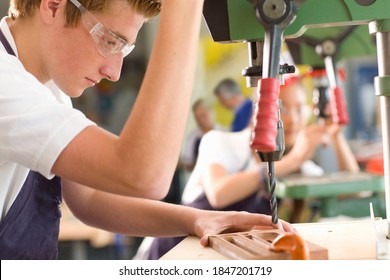 A Medium Closeup From A Side View Of A Serious Student Wearing Safety Glasses While Using The Drill Machine In A Vocational School