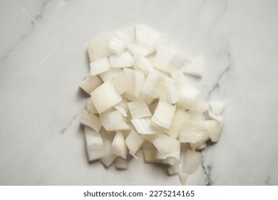 Medium diced onions on white marble background. Photo show how does onion sliced into medium cubes sliced and diced onions look like - Powered by Shutterstock