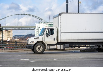 Medium Duty Rig Compact Size White Industrial Semi Truck For Local Deliveries Transporting Commercial Cargo For Timely Delivery In Dry Van Box Trailer Running On The Urban City Street Road