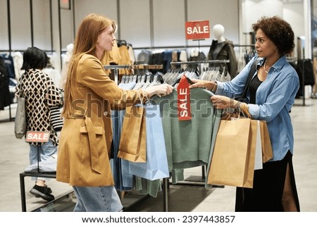 Medium full shot of two female customers fighting for jumper at mass market store