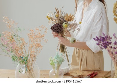 Medium height woman working with dried flowers assemble composition, decor and floristry concept